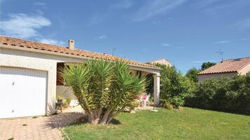 Une maison avec un toit en tuiles, un portail de garage et une pelouse bien entretenue.