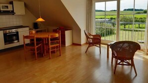 A spacious kitchen with a dining area, large windows, and a view of a green landscape. - Apartment 3 / o. r. - Ruegen-Fewo 47 (Putbus)