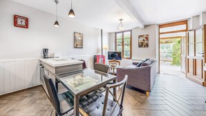 A modern kitchen with a glass dining table, a sofa, and a TV in a living area. - Appartement jolie vue rivière (Jaulgonne)