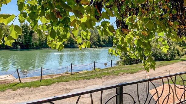 A riverside walkway with a metal railing, a clear view of a river, and lush greenery. - Appartement jolie vue rivière (Jaulgonne)