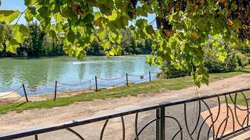 A riverside walkway with a metal railing, a clear view of a river, and lush greenery.