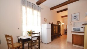 Eine gemütliche Küche mit Esstisch, Stühlen, Kühlschrank, Schrank und Mikrowelle.
