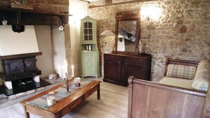Una habitación rústica con pared de piedra, muebles de madera, un armario verde y una cama de madera.