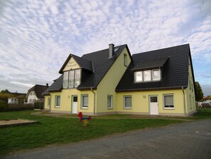 A two-story building with a sloped roof, a balcony on the upper floor, and a sign that reads "Haus Trifende".