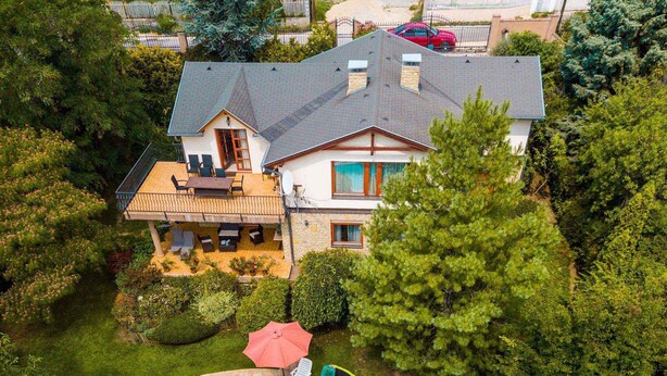 A two-story house with a swimming pool, surrounded by lush greenery and a fenced yard. - Holiday home with pool and view to Lake Balaton for families (Balatonalmádi)