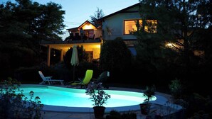 A house with a swimming pool, lounge chairs, and a covered patio area. - Holiday home with pool and view to Lake Balaton for families (Balatonalmádi)