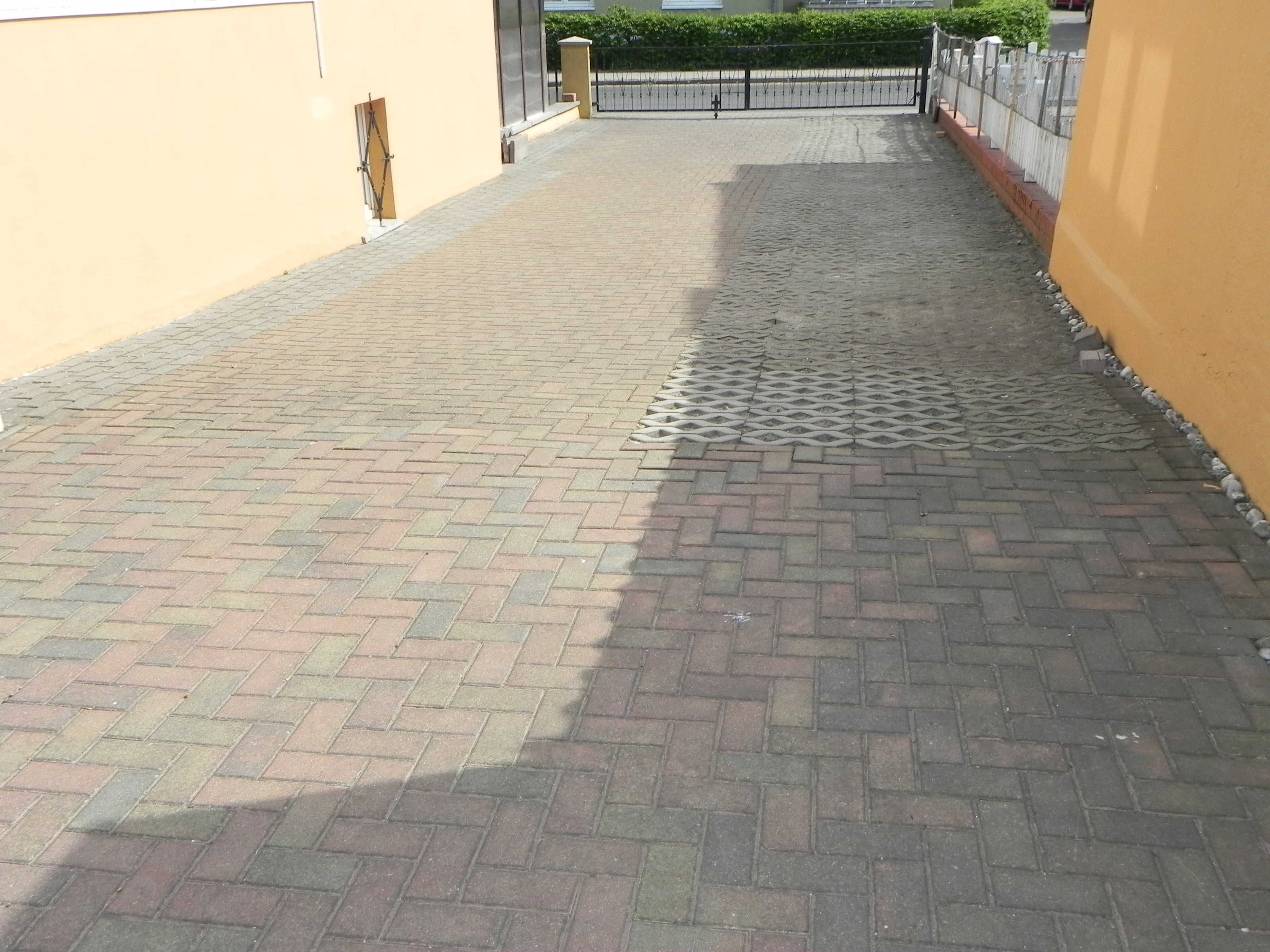A paved walkway with a metal grate and a gate at the end.
