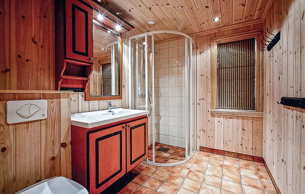 A wooden cabin bathroom with a sink, mirror, shower, and window. - Nice home in Hemsedal with sauna (Hemsedal)