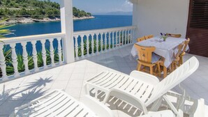 A terrace with white furniture, a table with a vase, and a view of the sea. - Stunning home in Vela Luka with kitchen (Vela Luka)