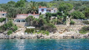 A coastal property with stone buildings, a pool, and a rocky shoreline. - Stunning home in Vela Luka with kitchen (Vela Luka)
