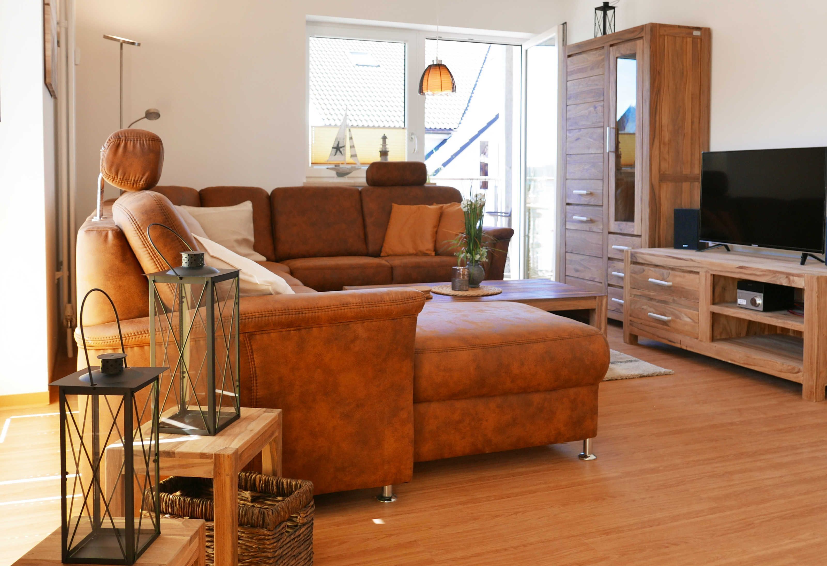 A modern living room with a brown sofa, wooden coffee table, and a TV stand.