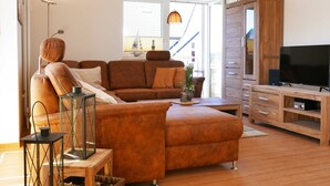 Un salon moderne avec un canapé marron, une table basse en bois et un meuble pour la télévision.