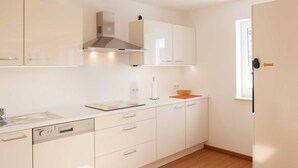 Une cuisine moderne avec des meubles blancs, un four encastré et une fenêtre.
