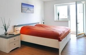 Un dormitorio con cama, mesita de noche, ventana con vistas y un cuadro en la pared.