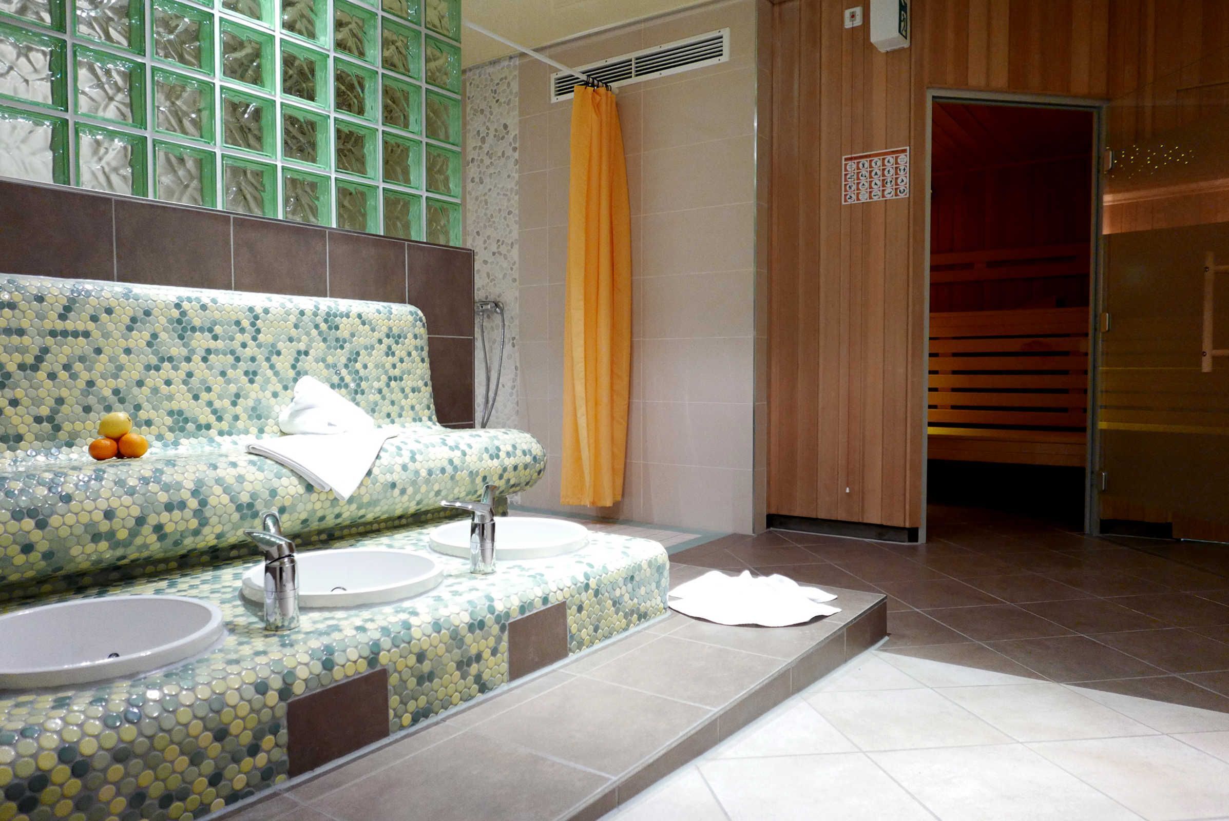 Une salle de bain avec un meuble-lavabo orné de mosaïques, deux vasques et un espace douche.