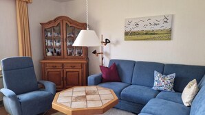 A living room with a blue sofa, a wooden cabinet, a round coffee table, and a hanging lamp.
