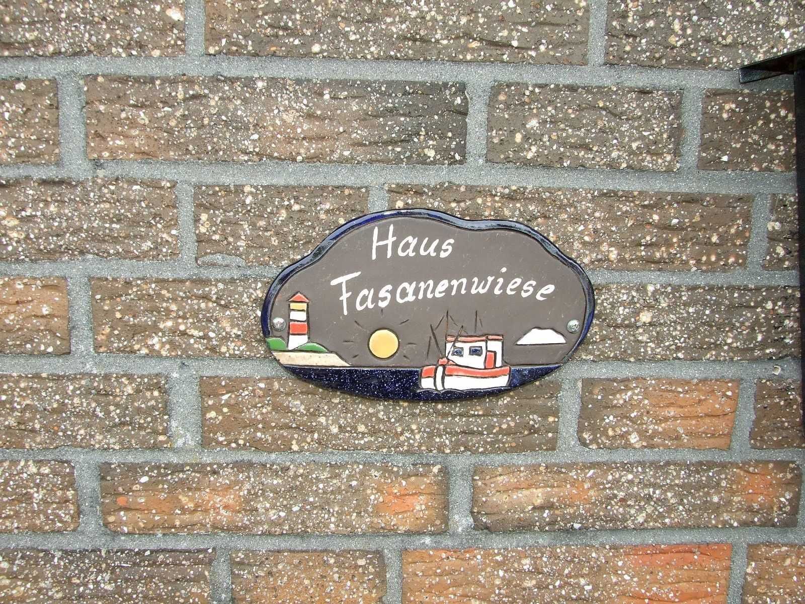 A brick wall with a sign that reads 'Haus Faschinenwiese' and features a lighthouse and a boat.