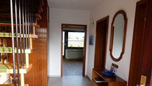 A hallway with a wooden staircase, a blue sink, and a mirror.