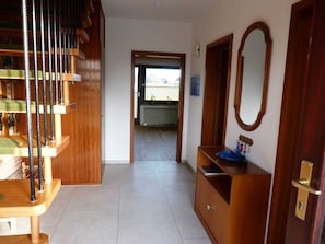 A hallway with a wooden staircase, a blue sink, and a mirror.