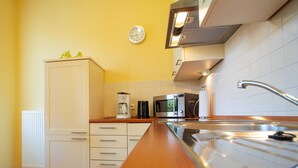 Une cuisine avec des meubles blancs, une machine à café, un four à micro-ondes et un évier en acier inoxydable.