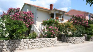 A house with a stone wall and flowering plants in front. - Holiday apartment mit Terrasse (Šilo)
