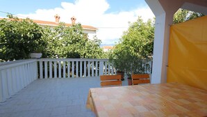 An outdoor patio with a checkered table and benches, surrounded by white railings and potted plants. - Holiday apartment mit Terrasse (Šilo)