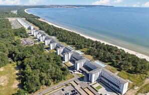 A coastal hotel with multiple buildings, a beach, and a parking lot.
