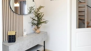 Un baño moderno con un lavamanos de mármol gris, un espejo redondo, una planta en maceta y un perchero.