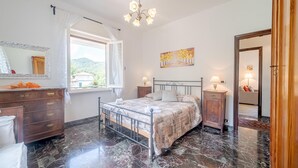Una camera da letto con un letto, un comodino, una cassettiera, uno specchio, un lampadario e un quadro.