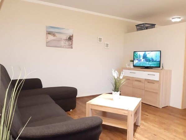 A living room with a sofa, a coffee table, a TV, and a cabinet.