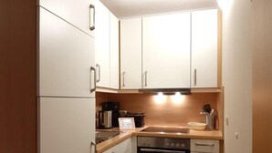 A compact kitchen with white cabinets, a stainless steel oven, and a sink. - (282) 2-room apartment-Hafenstraße - Apartment complex Yachthafenresidenz (Kühlungsborn)