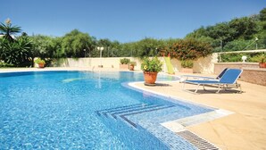 A clear blue swimming pool with tiled edges, surrounded by potted plants and a few lounge chairs. - Beach front home in Marbella (Marbella)