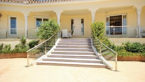 A set of outdoor stairs leading to a building entrance, flanked by glass railings and surrounded by greenery. - Beach front home in Marbella (Marbella)