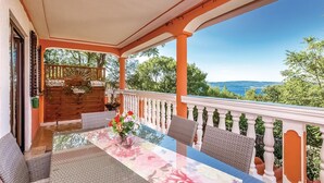 A balcony with a table set for dining, surrounded by wicker chairs, and a view of the landscape. - Beautiful apartment in Crikvenica (Crikvenica)