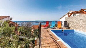 A pool area with a view of the sea, surrounded by a wooden deck and stone walls. - Beautiful apartment in Crikvenica (Crikvenica)