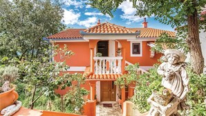 A house with a red facade, a balcony, and a statue of a woman holding a child. - Beautiful apartment in Crikvenica (Crikvenica)