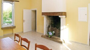Ein Essbereich mit Holztisch und -stühlen, einem Kamin und einem Fenster mit Blick auf Grünflächen.