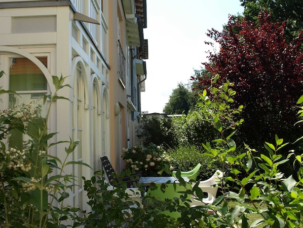 Ein Gebäude mit Balkon und Garten, bepflanzt mit verschiedenen Blumen und Pflanzen.