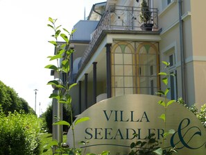 Schild für Villa Seeadler & Co. im klassischen Baustil, mit Balkon und großen Fenstern.