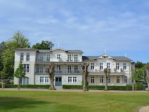 Ein großes, mehrgeschossiges Hotel mit symmetrischer Fassade, mehreren Balkonen und einem gepflegten Rasen im Vordergrund.