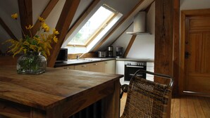 Een keuken met een houten tafel, een rieten stoel en een dakvenster.