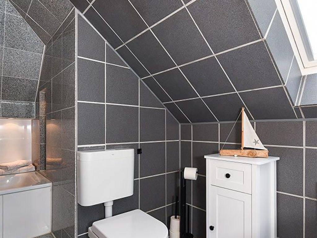Un baño con inodoro y mueble blancos, y un perchero para toallas.