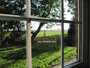 A window with a view of a grassy area and a wooden bench. - Huus Tide, Germany (Werdum)