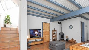 Un salon avec une télévision, une cheminée et un escalier.