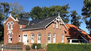 Un bâtiment en briques rouges, doté d’un toit à pignon et de bordures blanches.