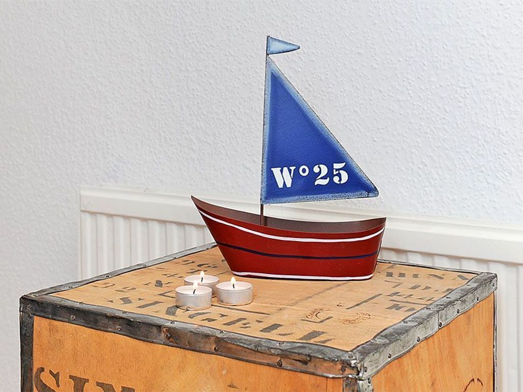 Ein Modellsegelboot mit der Nummer W25 auf einer Holzkiste im Vintage-Stil.