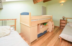 Un dormitorio con literas, un escritorio y una pequeña estantería.