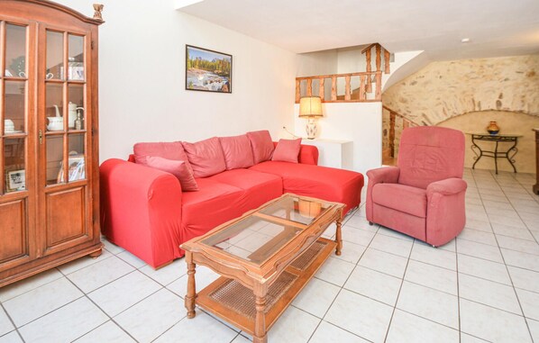 Una sala de estar con un sofá rojo, una mesa de centro de vidrio, un sillón rojo y un aparador de madera.