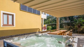 Un espacio de spa con hidromasaje, asientos al aire libre y un porche cubierto.