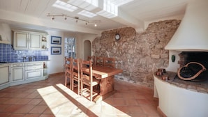 A kitchen with a stone wall, wooden table, and chairs.